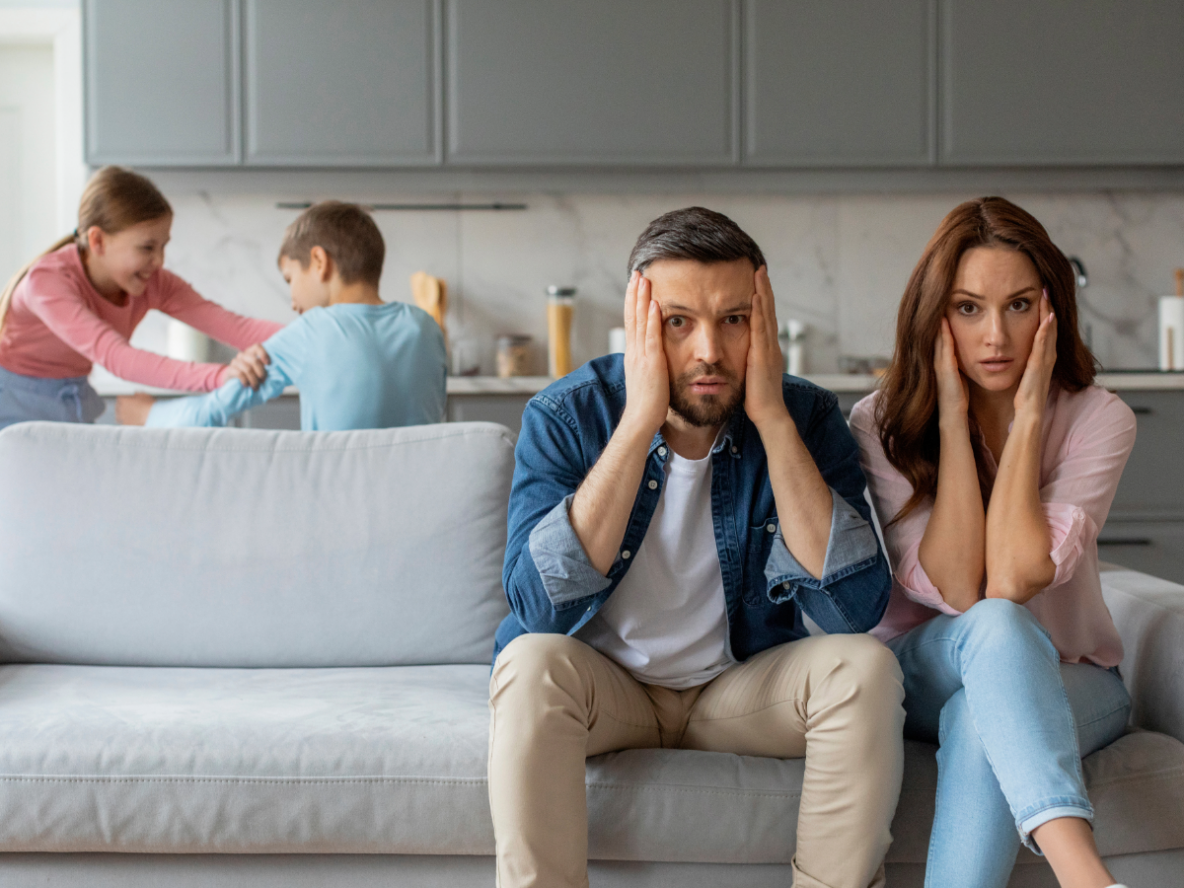 stressed out parents with kids arguing in the background